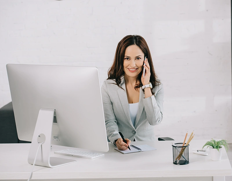 [:en]Assistentin am Handy mit Computer Screen in Vordergrund[:]